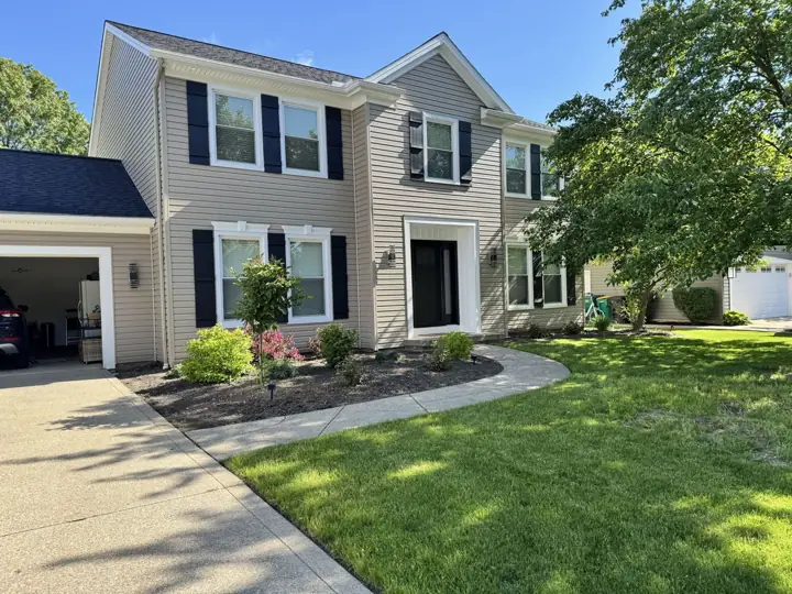 Beige siding, white window trim, and black shutters on a two-story home